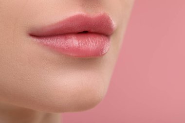 Pembe arka planda güzel dolgun dudakları olan genç bir kadın, yakın plan.