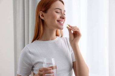 Evinde vitamin hapı alan güzel bir genç kadın.
