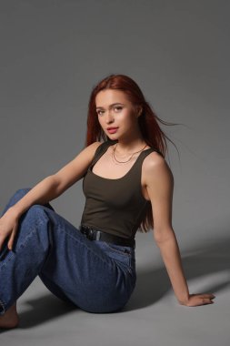 Gri arka planda oturan güzel genç kadın