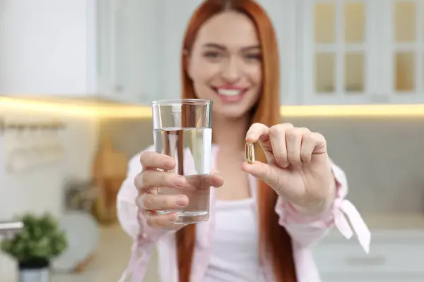 Beautiful young woman with vitamin pill and glass of water, selective focus