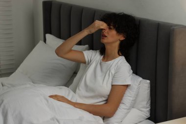 Geceleri yatakta baş ağrısı çeken genç bir kadın.