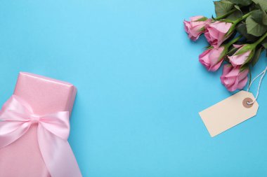 Anneler Günün kutlu olsun. Etiketli güzel güller ve açık mavi arka planda hediye kutusu, düz yatış. Metin için boşluk