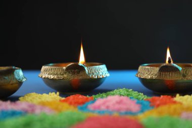 Diwali kutlaması. Diya lambaları ve renkli rangoli masa üzerinde siyah arkaplan, yakın plan