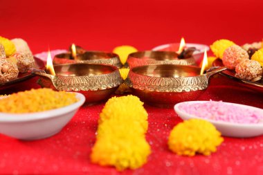 Diwali kutlaması. Diya lambaları ve parlak rangoli parlak kırmızı masa, yakın plan
