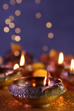 Diwali kutlaması. Parlak altın masa üzerindeki Diya lambası bulanık ışıklara karşı, yakın plan