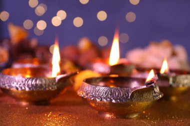 Diwali kutlaması. Bulanık ışıklara karşı parlak altın masa üzerindeki Diya lambaları, yakın plan