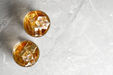 Açık gri desenli masada buzlu bardakta viski, düz uzanma. Metin için boşluk