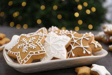 Gri masadaki süslü kurabiyeler bulanık Noel ışıklarına karşı, yakın plan.