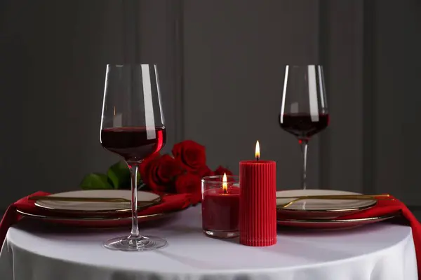 Place setting with candles and roses on white table. Romantic dinner