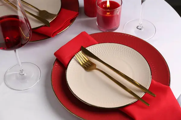 Place setting with candle for romantic dinner on white table