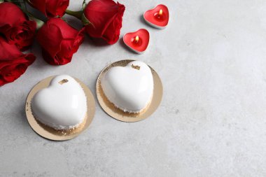 Sevgililer Günü. Lezzetli kalp şeklinde kekler, mumlar ve güller ışık masasında, düz yerde. Metin için boşluk