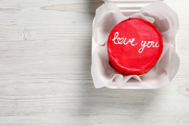 Bento keki ve Love You paket servis kutusuyla beyaz ahşap masa, üst manzara. Mesaj için yer var. Sevgililer Günü sürprizi