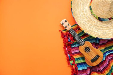 Meksika şapkası, gitar ve turuncu arka planda renkli panço düz yatıyordu. Metin için boşluk