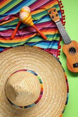 Meksika şapkası, gitar, marakas ve yeşil arka planda renkli panço.