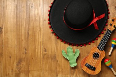 Meksika şapkası, marakas, oyuncak kaktüs ve tahta arka planda gitar, düz yatış. Metin için boşluk