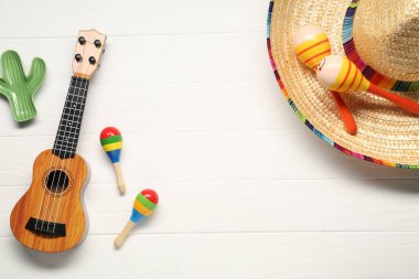 Meksika şapkası, marakas, beyaz ahşap arka planda oyuncak kaktüs ve gitar. Metin için boşluk