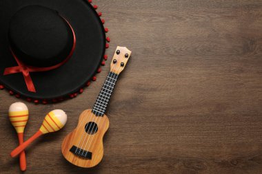 Meksika şapkası, marakas ve gitar tahta arka planda, düz yatış. Metin için boşluk