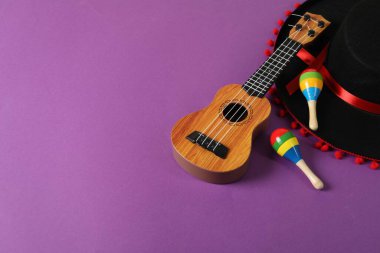 Siyah Flamenko şapka, ukulele ve marakas mor masada. Metin için boşluk