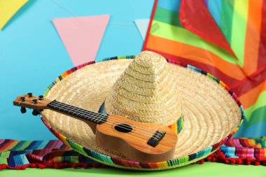 Meksika şapkası, panço ve ukulele yeşil masada, yakın plan.
