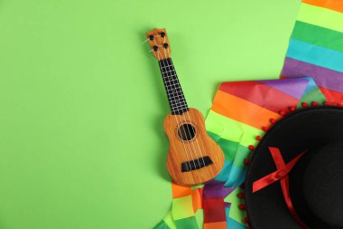 Yeşil arka planda siyah Flamenko şapka ve ukulele, üst manzara. Metin için boşluk