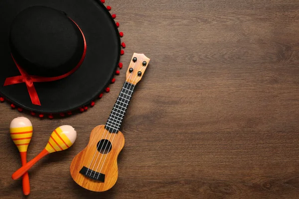 Meksika şapkası, marakas ve gitar tahta arka planda, düz yatış. Metin için boşluk