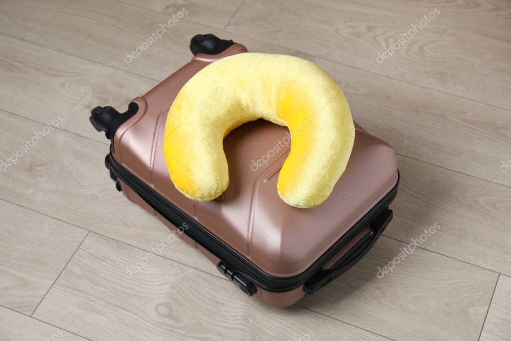 Yellow travel pillow and suitcase on floor