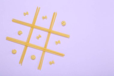 Leylak arkaplanda farklı türde makarna ile yapılan tik tak parmak oyunu, üst görünüm