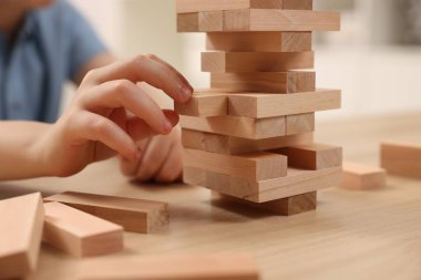Çocuk içeride ahşap masada Jenga oynuyor, yakın plan.