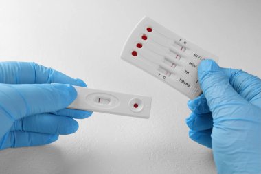 Doktor beyaz masada iki adet kullan-at test tutuyor, yakın plan.