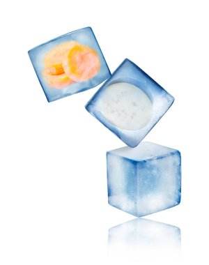 Donmuş havuç, patlıcan ve buz küpü beyaz arka plana düşüyor.