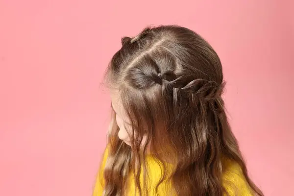 Cute little girl with braided hair on pink background