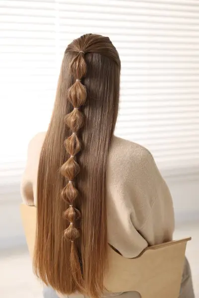 Woman with braided hair indoors, back view
