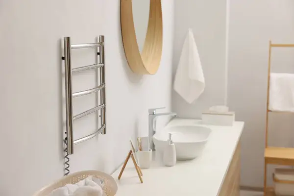 Heated towel rail on white wall in bathroom