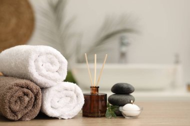 Spa kompozisyonu. Yuvarlak havlular, aroma yayıcı, masaj taşları ve kapalı masa üzerinde yanan mum. Metin için boşluk