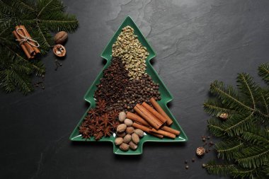 Farklı baharatlar, fındıklar ve köknar dalları koyu gri desenli masa, düz yatıyordu.