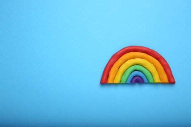 Açık mavi arka planda plastikten yapılmış güzel bir gökkuşağı, üst manzara. Metin için boşluk