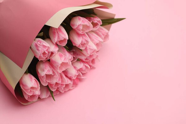 Beautiful bouquet of fresh tulips on pink background. Space for text