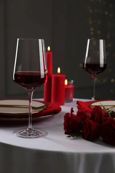 Place setting with roses and candles on white table. Romantic dinner