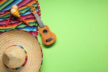 Meksika şapkası, gitar, marakas ve yeşil arka planda renkli panço. Metin için boşluk