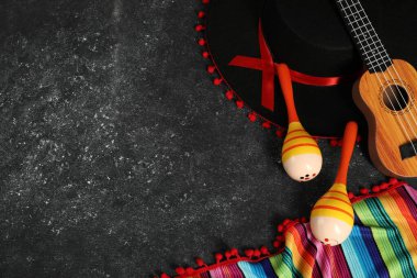 Siyah Flamenko şapka, ukulele, panço ve marakas koyu dokulu masa, düz yatak. Metin için boşluk
