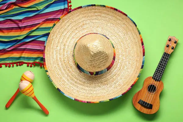 Meksika şapkası, gitar, marakas ve yeşil arka planda renkli panço.