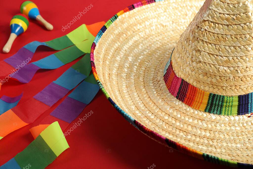 Mexican sombrero hat and maracas on red background, closeup