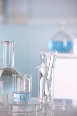 Laboratuvar analizi. Kapalı alandaki beyaz masa üzerinde sıvı bulunan farklı camlar.