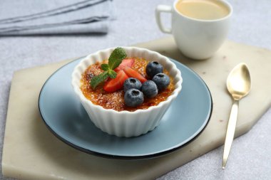 Böğürtlenli ve naneli nefis creme brulee. Gri masada servis edilir, yakın plan.