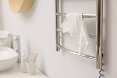 Banyodaki beyaz duvarda iç çamaşırı olan ısıtmalı havlu tırabzanı, yakın plan.