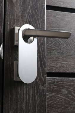 Kapalı ahşap kapı. Metal sapında boş askı var. Yakın plan.
