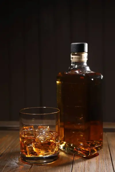 黒い背景に対する木枠のガラスとボトルの氷の立方体が付いているウイスキー — ストック写真