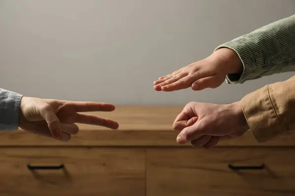 People playing rock, paper and scissors indoors, closeup