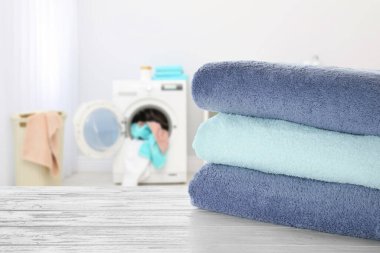 Çamaşır odasındaki beyaz ahşap masaya katlanmış temiz havlular, mesaj için yer.