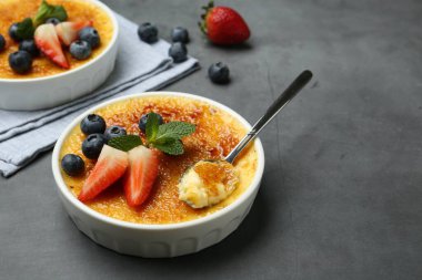 Lezzetli creme brulee kasede böğürtlen ve gri masada kaşık. Metin için boşluk